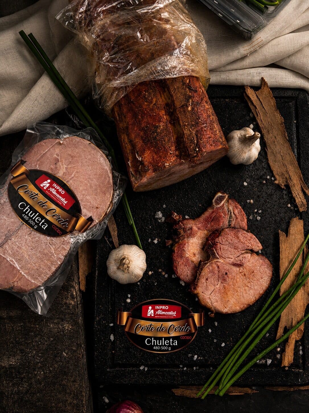 Chuleta de cerdo empacada al vacío con etiqueta Inproalimentos, junto a la pieza ahumada y dos chuletas cortadas